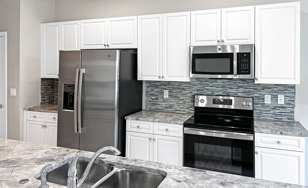 Spacious and well lit kitchen with wood floors and stainless steel appliances 