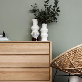 decor on a tall, wooden dresser next to a papasan chair with a throw